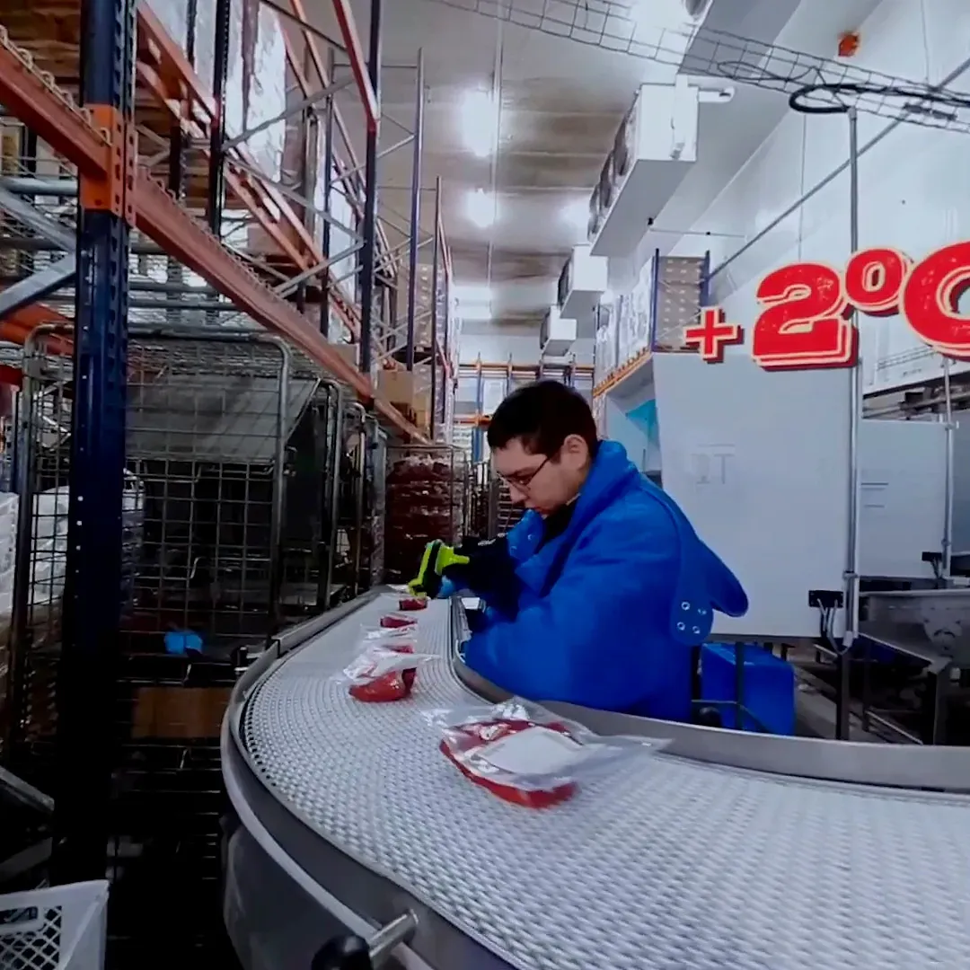 Opérateur qui prépare de la viande au bord d’un convoyeur, application VR de découverte d’une usine et du métier de boucher