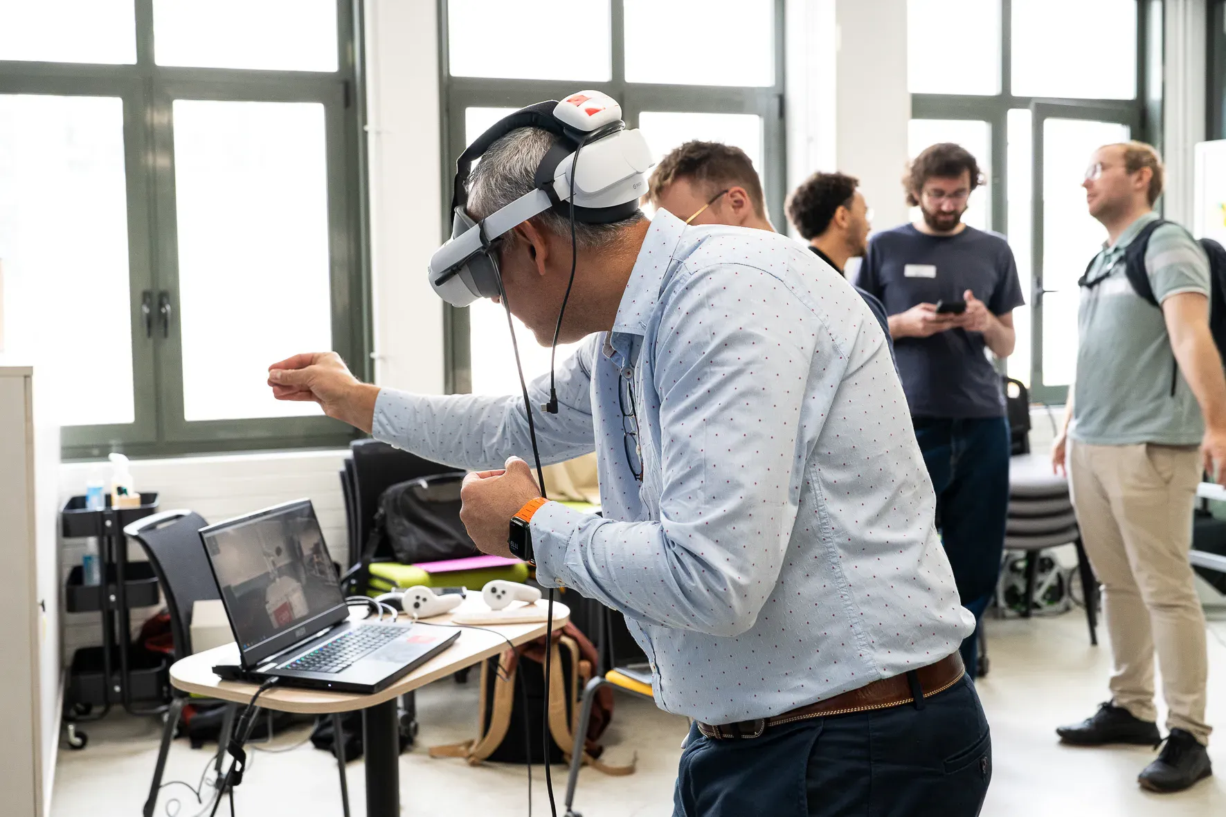 Un participant équipé d’un casque de réalité virtuelle se penche pour saisir un objet virtuel.