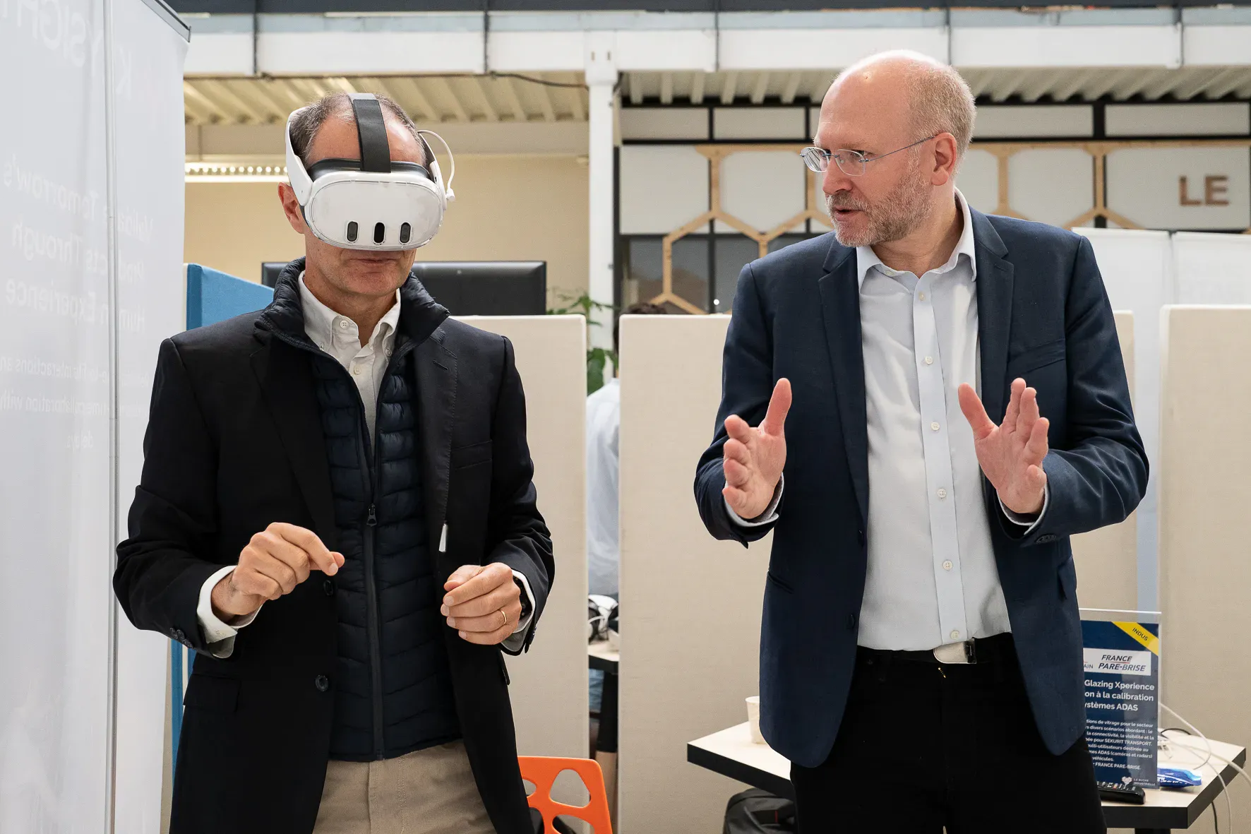 Un intervenant explique l’expérience à un visiteur équipé d’un casque de réalité virtuelle.