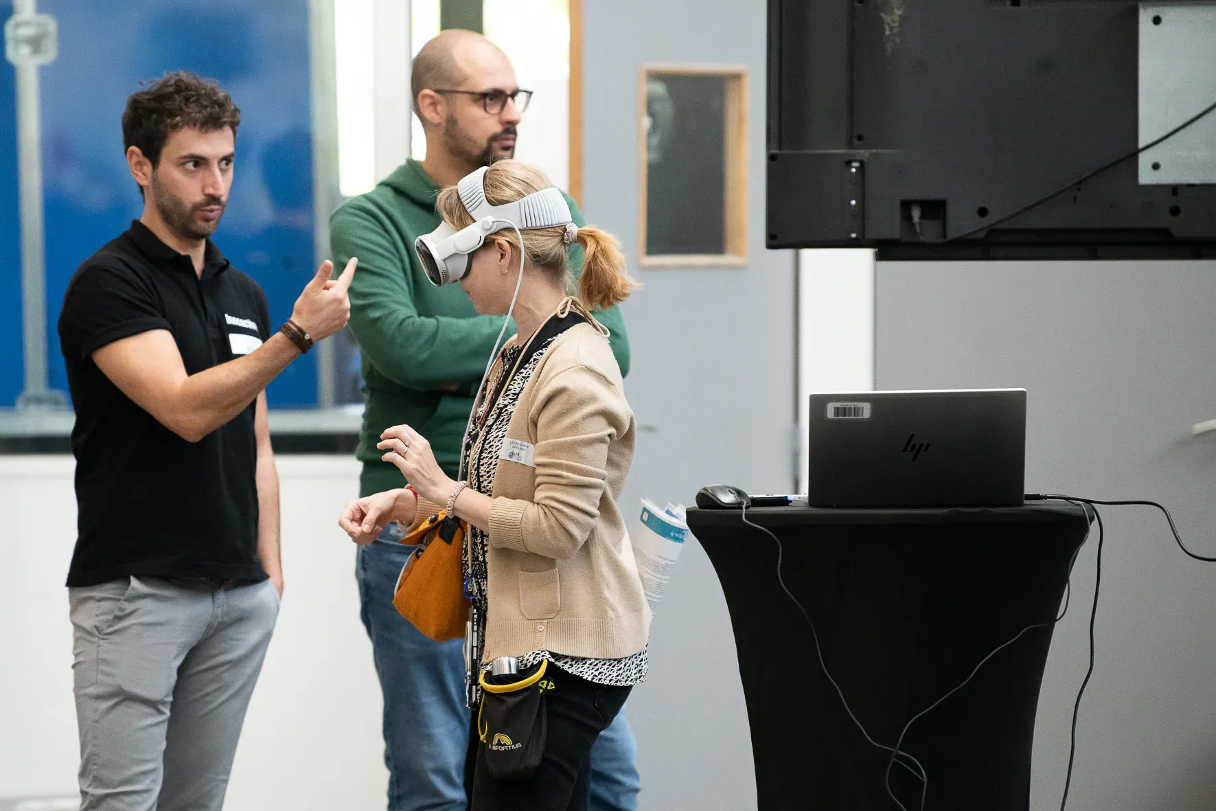 Un intervenant guide une visiteuse qui découvre une expérience en casque de réalité virtuelle.