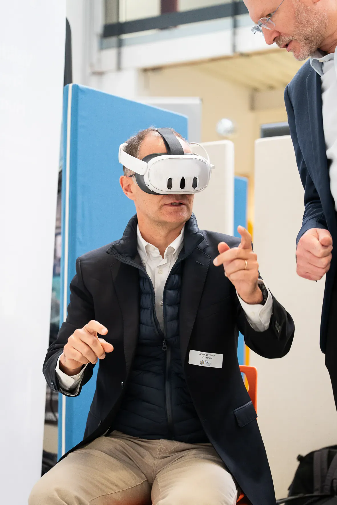 Un visiteur assis en casque de réalité virtuelle réagit à la scène qui l’entoure.